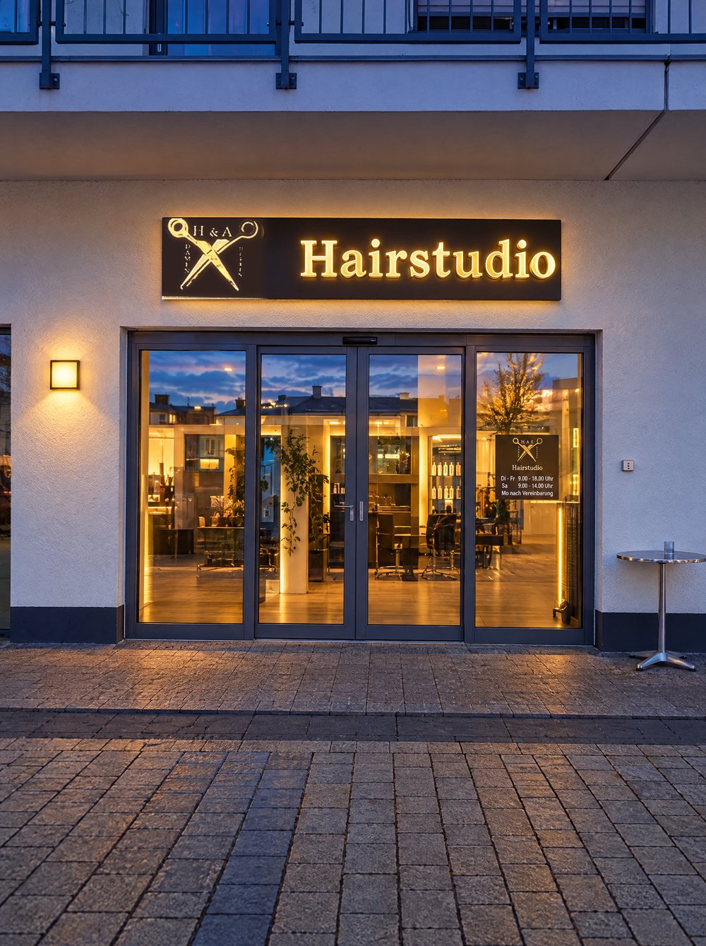 Ladenfront des H&A Hairstudio am Bahnhofsplatz am Abend